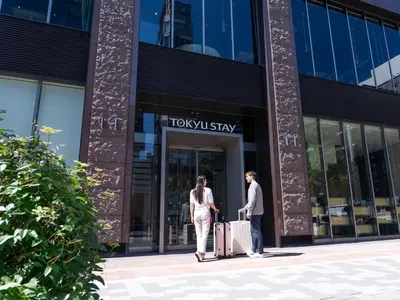 two people standing outside of a building with luggage at Tokyu Stay Ginza in Tokyo
