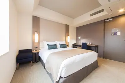 a hotel room with a large bed and a blue chair at Tokyu Stay Ginza in Tokyo