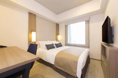 a hotel room with a bed and a flat screen tv at Tokyu Stay Ginza in Tokyo
