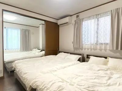 two beds in a room with white sheets and windows at kSF\u6c60\u888b\u672c\u753a2\u4e01\u76ee in Tokyo