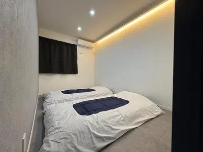 a small bedroom with a bed with white sheets at COTO Premium Kyodo in Tokyo