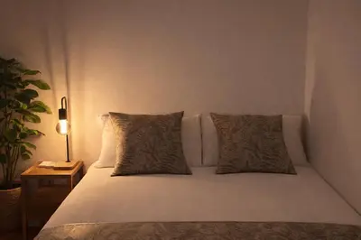 a white bed with two pillows and a night stand at louis stage \u897f\u30f6\u539f 103\u5ba4 in Tokyo