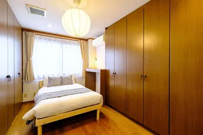 a bedroom with a bed and wooden cabinets and a window at F-City \u4e2d\u845b\u897f iii in Tokyo
