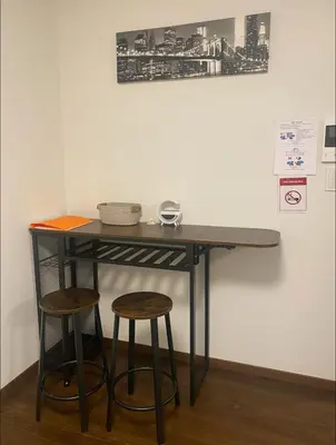 a table with two stools in front of a wall at Nexus Vill Morishita in Tokyo