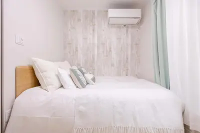 a bedroom with a bed with white sheets and pillows at Shinjuku Private Family House in Tokyo