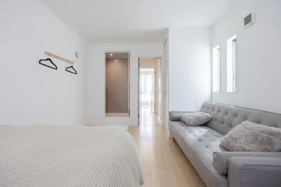 a white bedroom with a bed and a couch at Shinjuku Private Family House in Tokyo