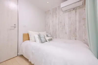 a bedroom with a bed with white sheets and pillows at Shinjuku Private Family House in Tokyo
