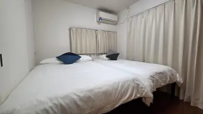 a bedroom with a white bed with blue pillows at Nakano OSHIYO House in Tokyo