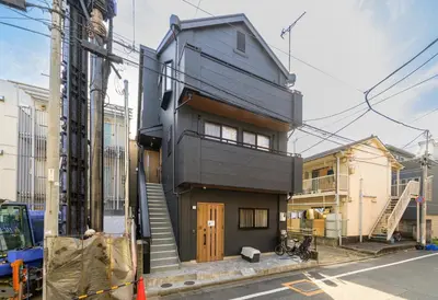 a black house with a wooden door on a street at Chill Place 120 Ayase in Tokyo