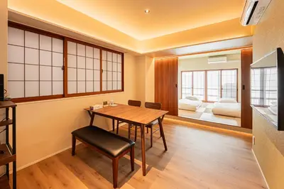 a dining room with a table and a bedroom at Cocono Apartment Hotel in Tokyo