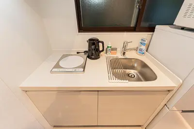 a kitchen counter with a sink and a microwave at Cocono Apartment Hotel in Tokyo