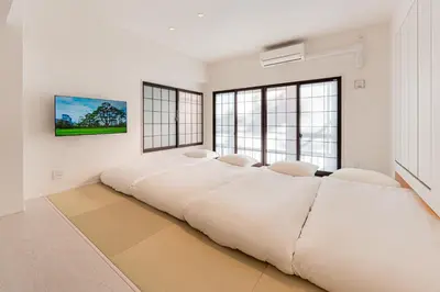 a large white bed in a room with windows at Cocono Apartment Hotel in Tokyo