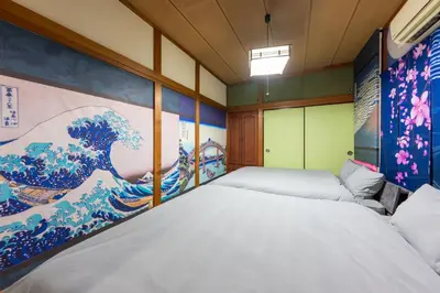 a bedroom with two beds and a painting on the wall at 1200IN&OUT 5people 35m2 2Queenbed! 1sofabed! Exclusive house Shinjuku 18 minutes Shibuya 22 minutesIkebukuro 11 minutes in Tokyo