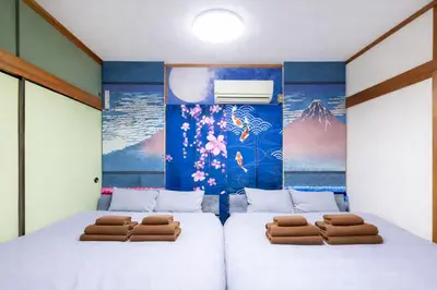 two beds in a room with a mural at 1200IN&OUT 5people 35m2 2Queenbed! 1sofabed! Exclusive house Shinjuku 18 minutes Shibuya 22 minutesIkebukuro 11 minutes in Tokyo