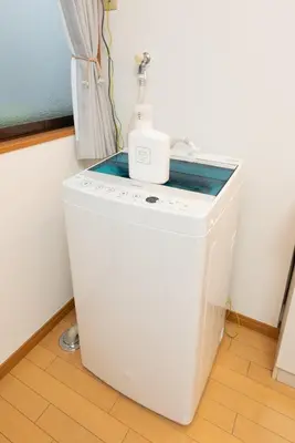 a washing machine with a bottle on top of it at 101 Tokyo Ikebukuro apartment near Pokemon Center in Tokyo