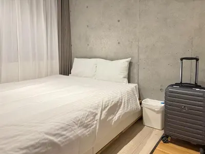 a bed with white sheets and a suitcase in a room at Minami-Magome # 101 in Tokyo