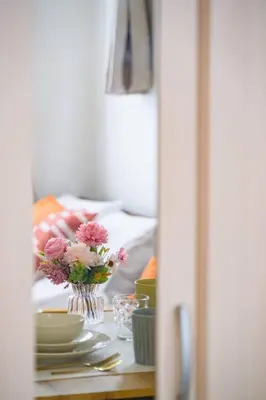 a table with plates and a vase of flowers on it at Sakura Court Ebisu 101 in Tokyo