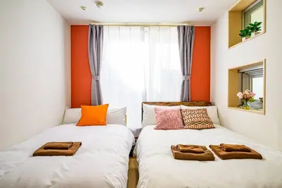 two beds in a room with orange walls at Sakura Court Ebisu 105 in Tokyo