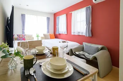a living room with a dining table and a red wall at Sakura Court Ebisu 205 in Tokyo