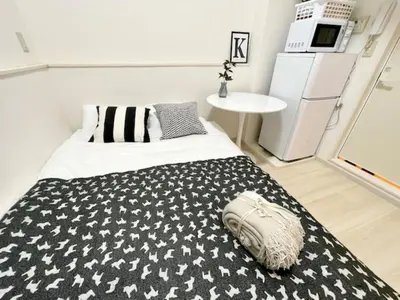 a bedroom with a black and white bed and a refrigerator at \u6771\u4eac\u65b0\u5bbf\u306e\u5bbf in Tokyo