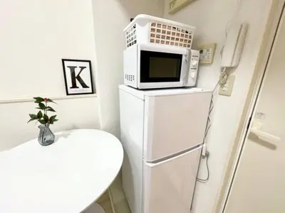 a microwave sitting on top of a refrigerator at \u6771\u4eac\u65b0\u5bbf\u306e\u5bbf in Tokyo