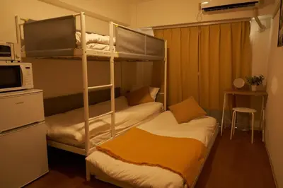 a bedroom with two bunk beds and a microwave at Sgc\u4e16\u7530\u8c371\u4e01\u76ee in Tokyo