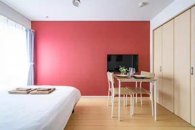 a bedroom with a red wall and a table and a bed at Sakura Court Ebisu 303 in Tokyo