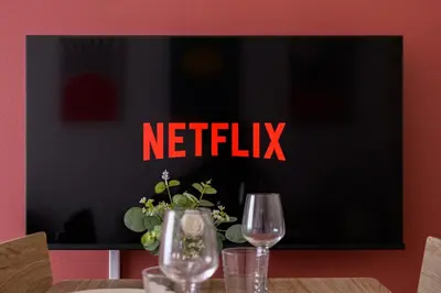 a tv with a netflix sign on a table with two wine glasses at Sakura Court Ebisu 303 in Tokyo
