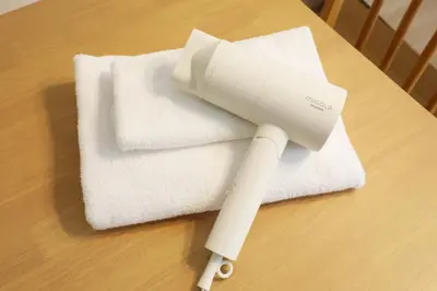 a white hair dryer on top of towels on a table at Sakura Court Ebisu 305 in Tokyo