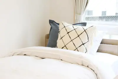 a bed with white sheets and pillows next to a window at Sakura Court Ebisu 305 in Tokyo