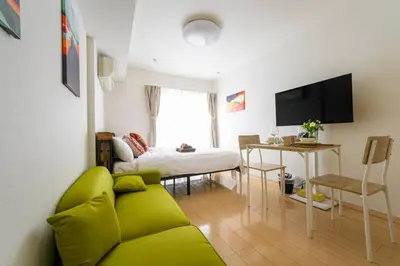 a living room with a green couch and a bed at Sakura Court Ebisu 403 in Tokyo