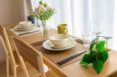 a wooden table with plates and bowls and flowers on it at Sakura Court Ebisu 405 in Tokyo
