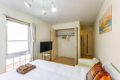 a bedroom with a white bed and a television at Sakura Court Ebisu 405 in Tokyo