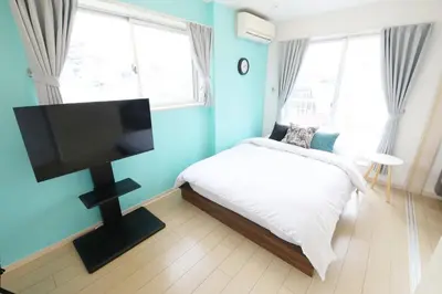 a bedroom with a bed and a flat screen tv at Sakura Court Ebisu 501 in Tokyo