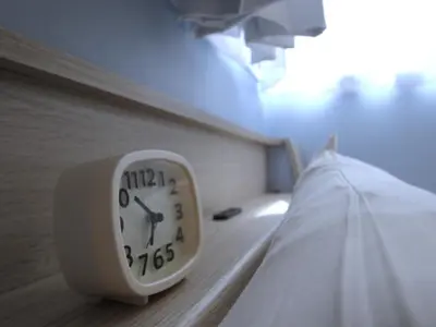 a clock sitting on the side of a bed at Cassyta Gotanda Zeko-Residence in Tokyo