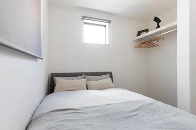 a bedroom with a bed with white sheets and a window at Jack of clubs inn in Tokyo