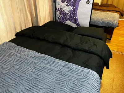 a bed with a black comforter and pillows at Komone House in Tokyo