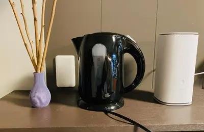 a black coffee pot sitting on a table next to a vase at Komone House in Tokyo