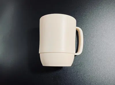 a white coffee cup sitting on a black table at Komone House in Tokyo
