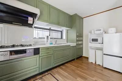 a kitchen with green cabinets and a white refrigerator at BF Stay Shinjukugyoen in Tokyo