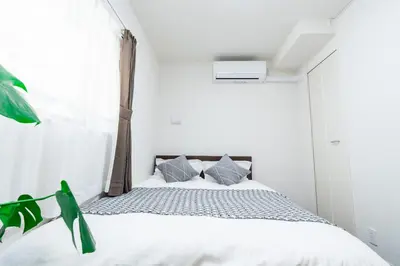 a white bedroom with a bed and a window at Sunbright Asakusa 201 in Tokyo