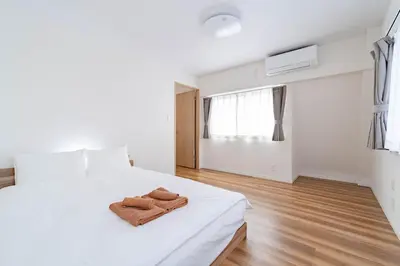 a white bedroom with a bed with two towels on it at \u4e80\u67095\u4e01\u76ee401 in Tokyo