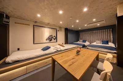a room with two beds and a wooden table at ZENBASE Ryogoku in Tokyo