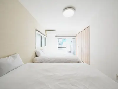 a bedroom with two beds and a window at IGETA HOUSE Shibuya in Tokyo