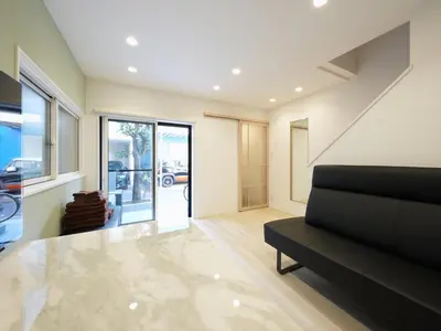 a living room with a black couch and a glass door at IGETA HOUSE Shibuya in Tokyo