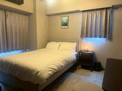 a bedroom with a bed and a night stand with a lamp at ROLES Ryusen 901 in Tokyo