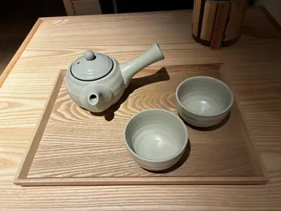 a tea kettle and two bowls on a wooden table at Komorebi Rill Hotel HANA in Tokyo