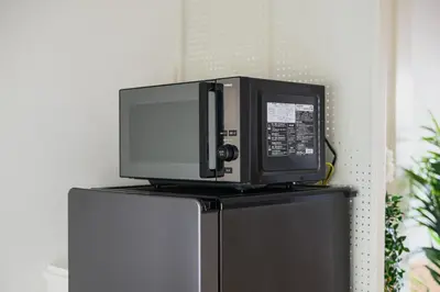 a microwave oven sitting on top of a refrigerator at Direct Haneda Access &Onsen 1-min Walk SAMURAI STAY ZEN in Tokyo