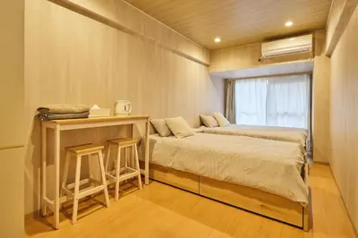 a bedroom with two beds and a table and a window at \u65b0\u5bbf\u5e02\u4e2d\u5fc3\u7d27\u90bb\u6b4c\u821e\u4f0e\u753a\u65b0\u5bbf\u30b4\u30fc\u30eb\u30c7\u30f3\u885713 in Tokyo