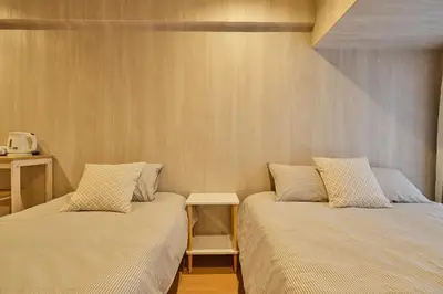 a bedroom with two beds and a small table at \u65b0\u5bbf\u5e02\u4e2d\u5fc3\u7d27\u90bb\u6b4c\u821e\u4f0e\u753a\u65b0\u5bbf\u30b4\u30fc\u30eb\u30c7\u30f3\u885713 in Tokyo